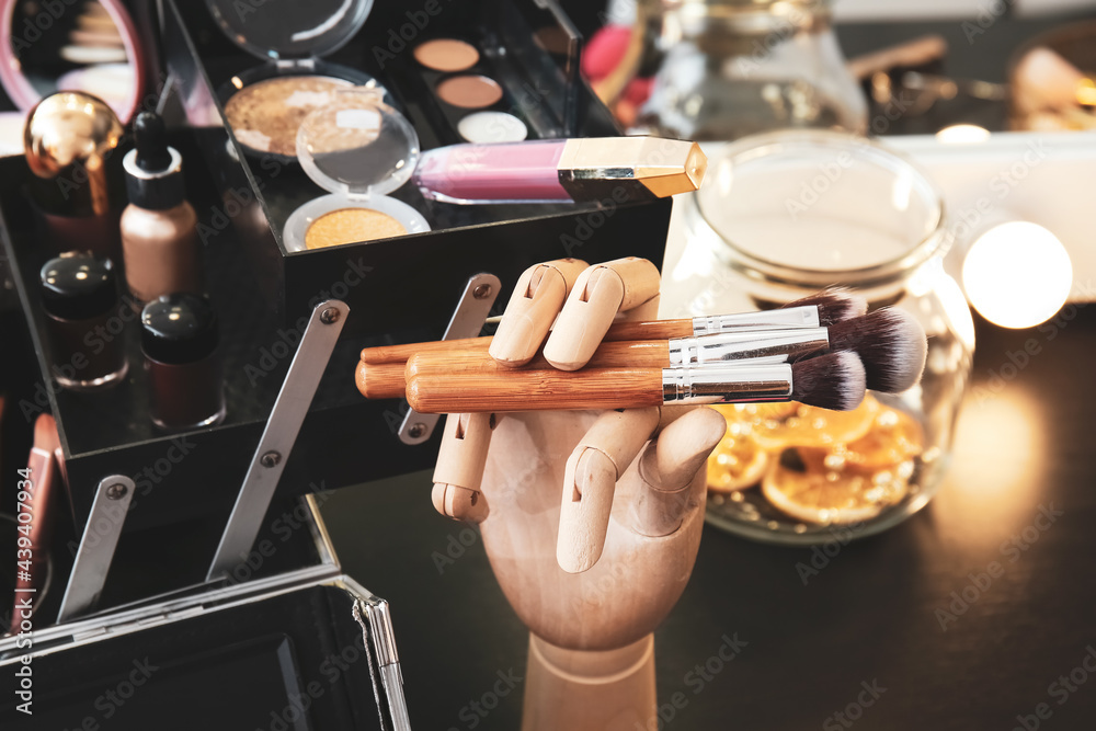 Wooden hand with makeup brushes on dressing table, closeup