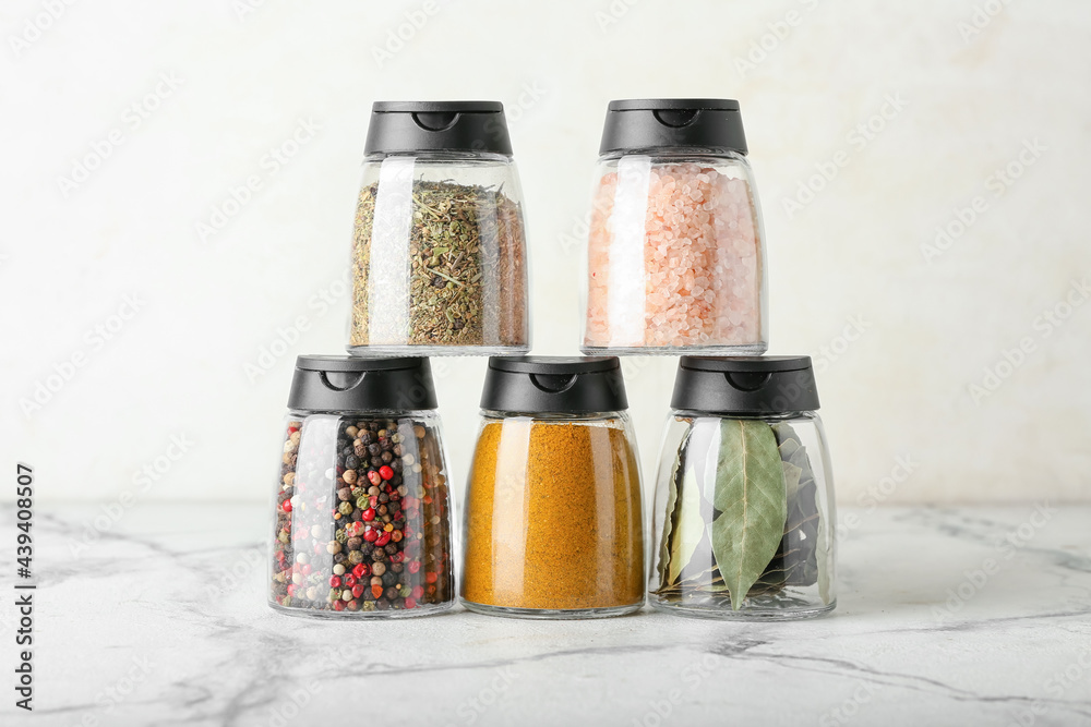 Jars with different spices on light background