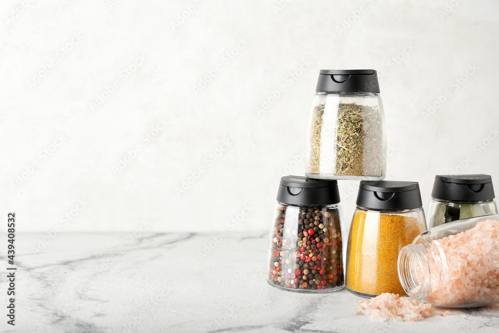 Jars with different spices on light background