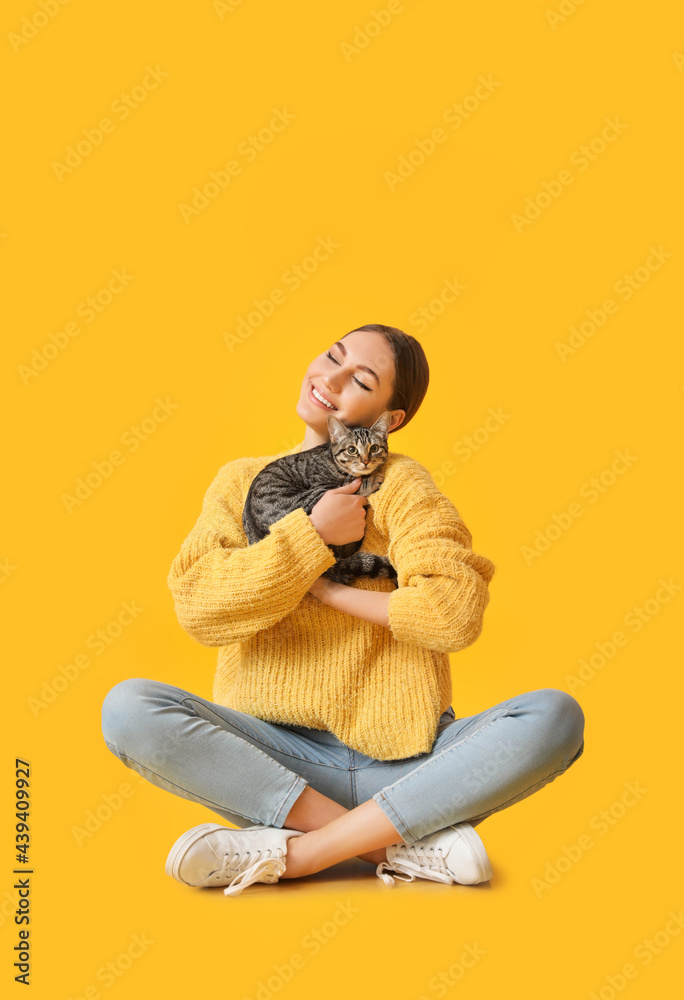 Beautiful young woman with cute cat on color background