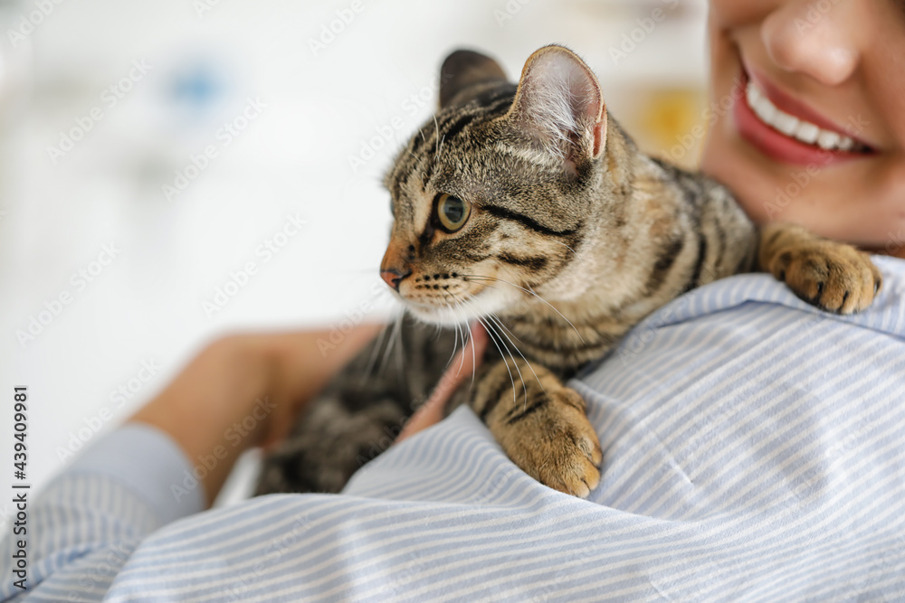 Young woman with cute cat at home, closeup