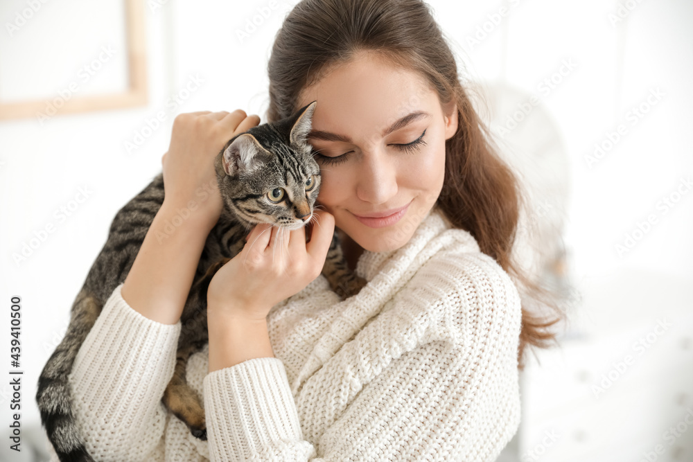 Beautiful young woman with cute cat at home