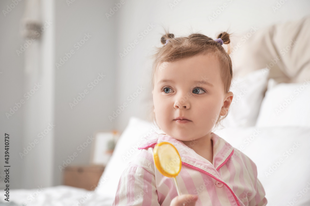 Cute little girl with lollipop in bedroom, closeup