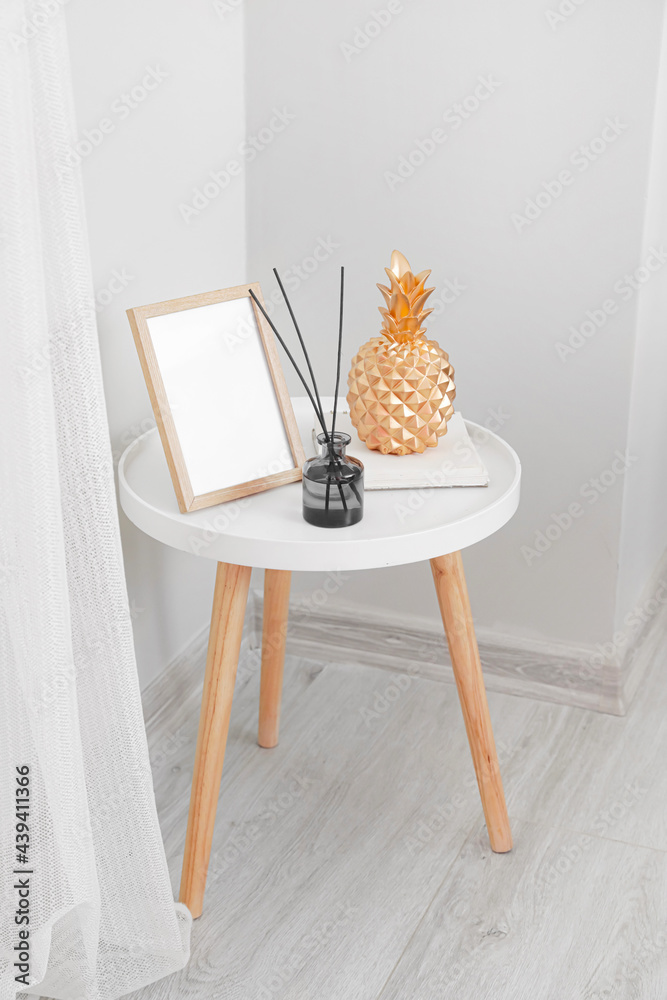 Reed diffuser with frame and decor on table in room