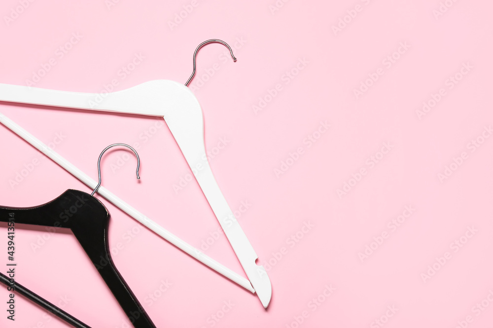 Stylish clothes hangers on color background