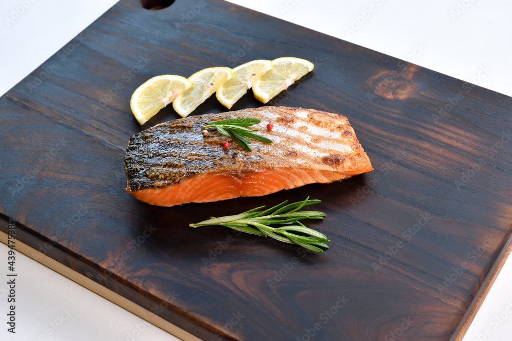 Grilled salmon steak with ingredients on wooden cutting board in the kitchen