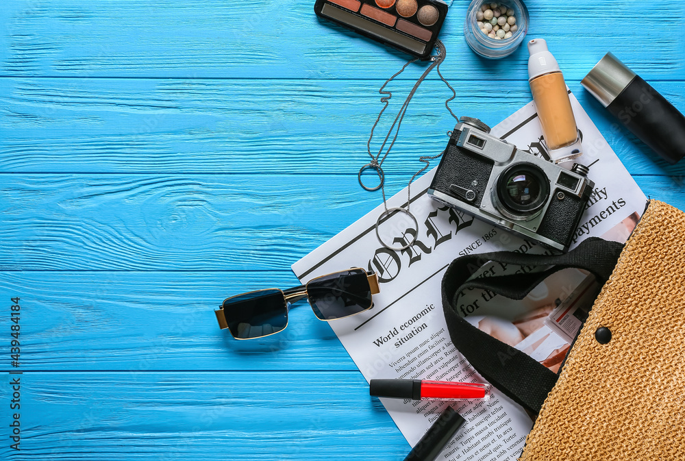 Stylish female accessories with newspaper on color wooden background