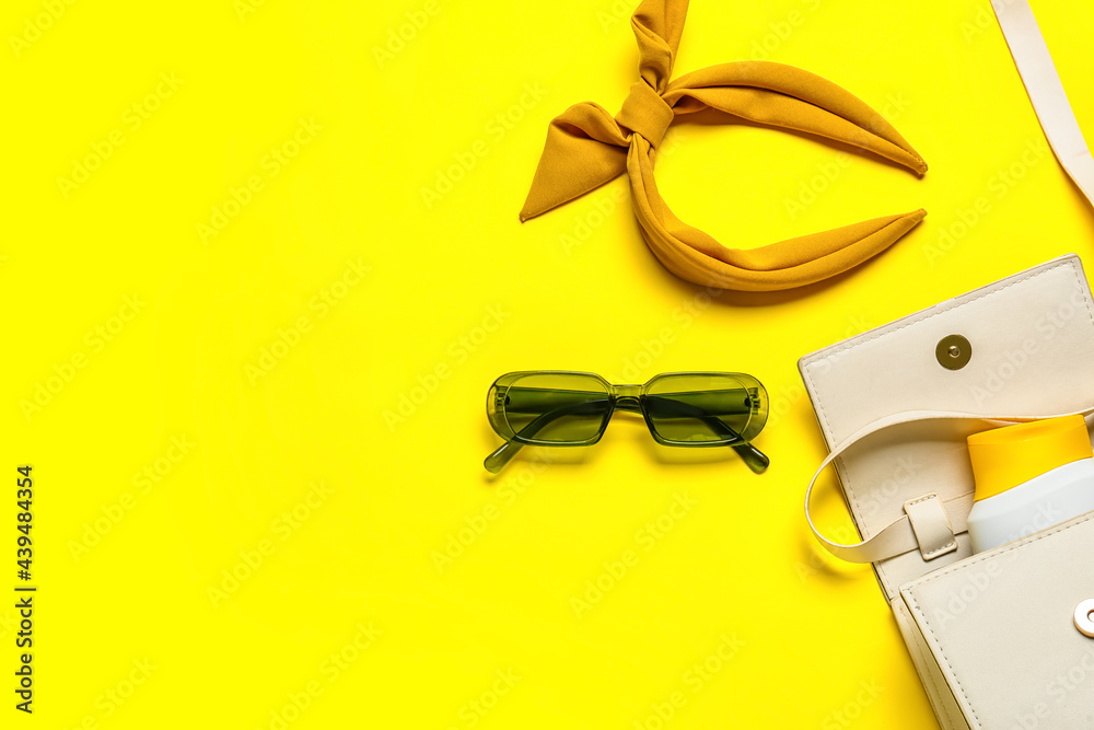 Stylish female accessories with sunscreen on color background