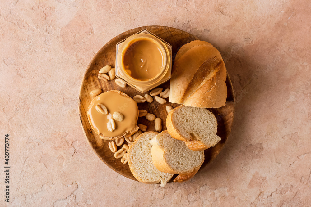 Jar with tasty peanut butter and bread on color background