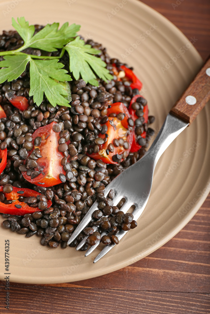 Plate with tasty cooked lentils and vegetables on table, closeup