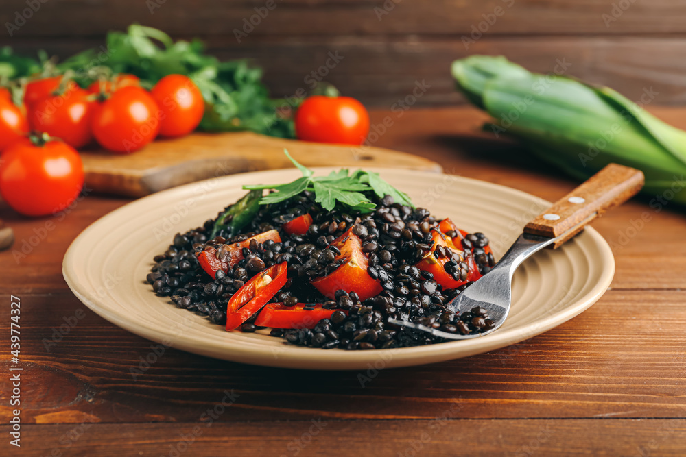 Plate with tasty cooked lentils and vegetables on table