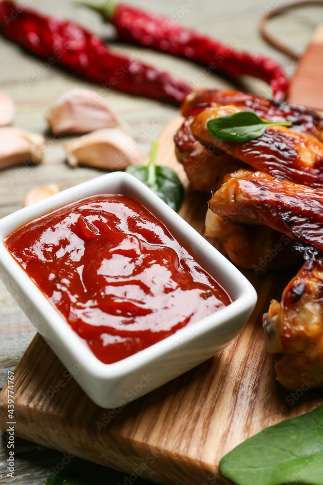 Roasted chicken wings and barbecue sauce on wooden background