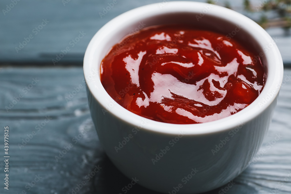 Bowl with tasty barbecue sauce on dark wooden background