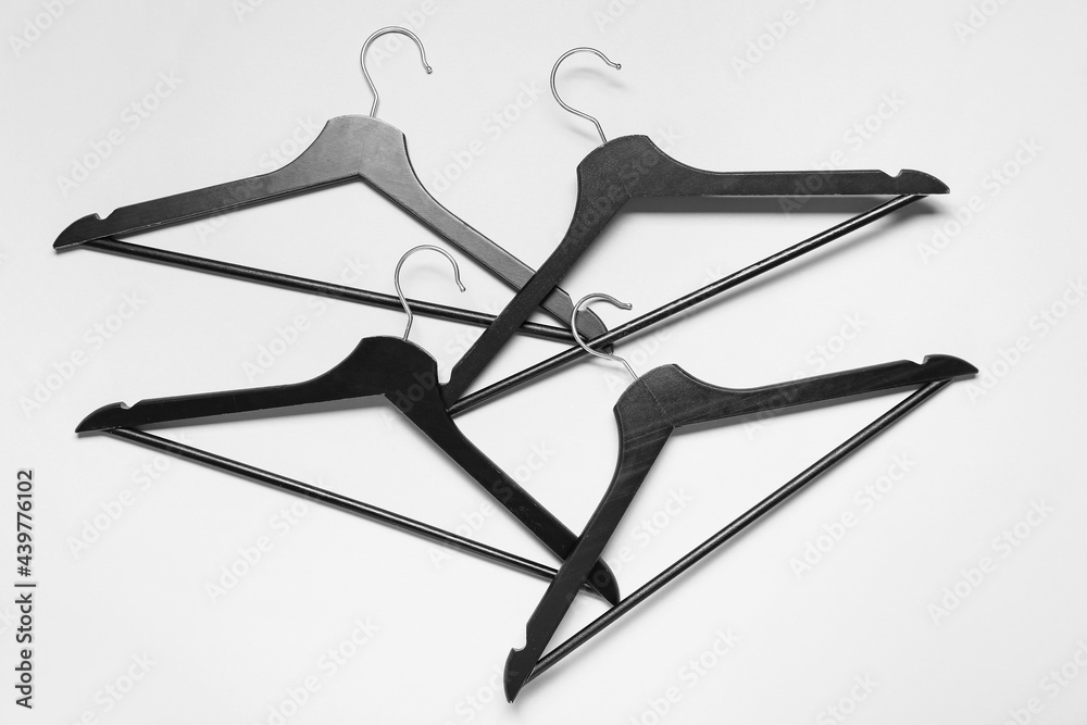 Stylish clothes hangers on light background