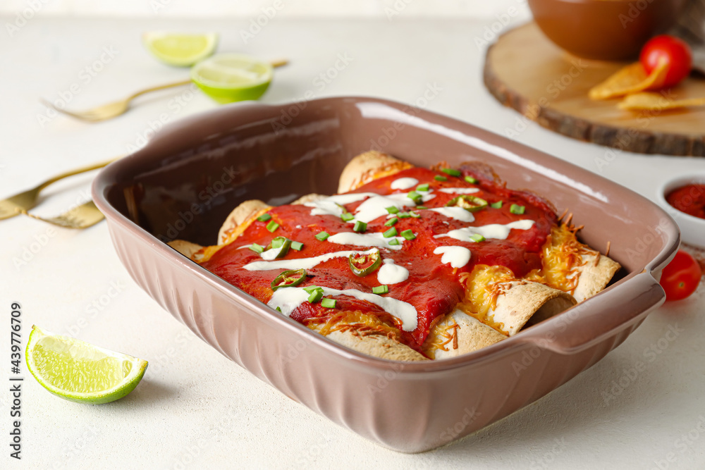 Baking dish with tasty cooked enchilada on table