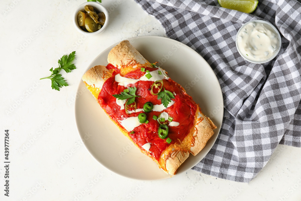 Plate with tasty cooked enchilada on white background