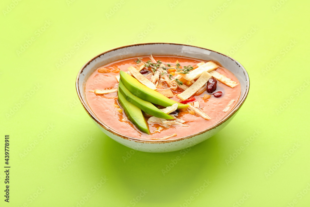 Bowl of tasty chicken enchilada soup on color background