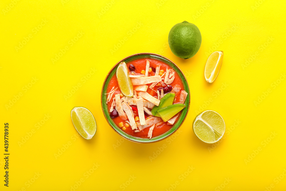 Bowl of tasty chicken enchilada soup on color background