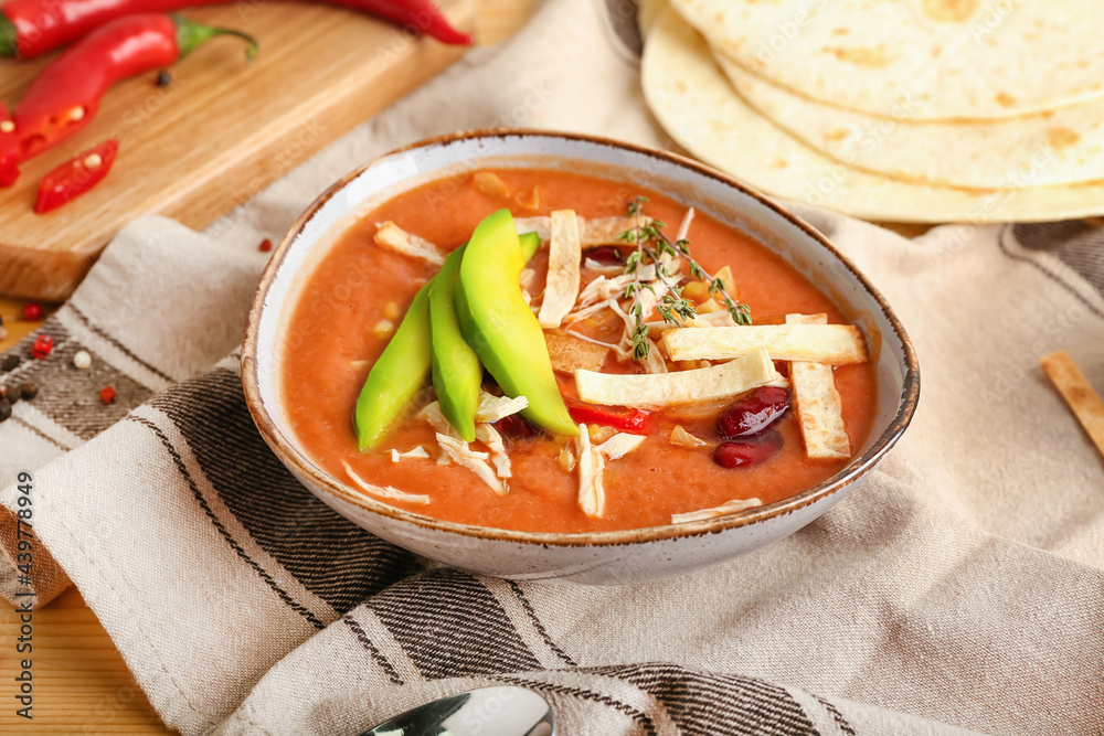 Bowl of tasty chicken enchilada soup on table