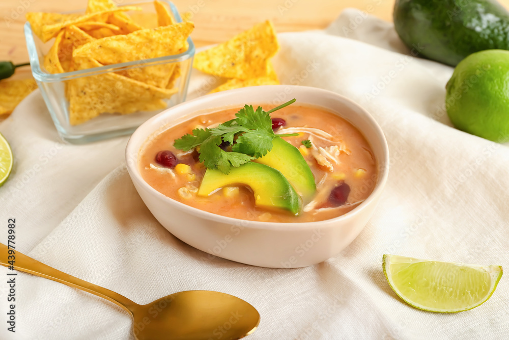 Bowl of tasty chicken enchilada soup on table