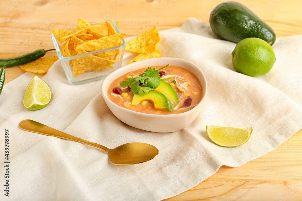 Bowl of tasty chicken enchilada soup on table