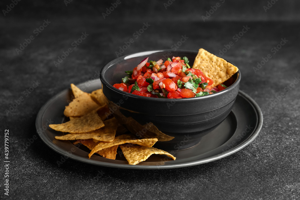 Bowl of tasty Pico de Gallo salsa and nachos on dark background