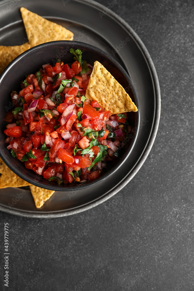 Bowl of tasty Pico de Gallo salsa and nachos on dark background