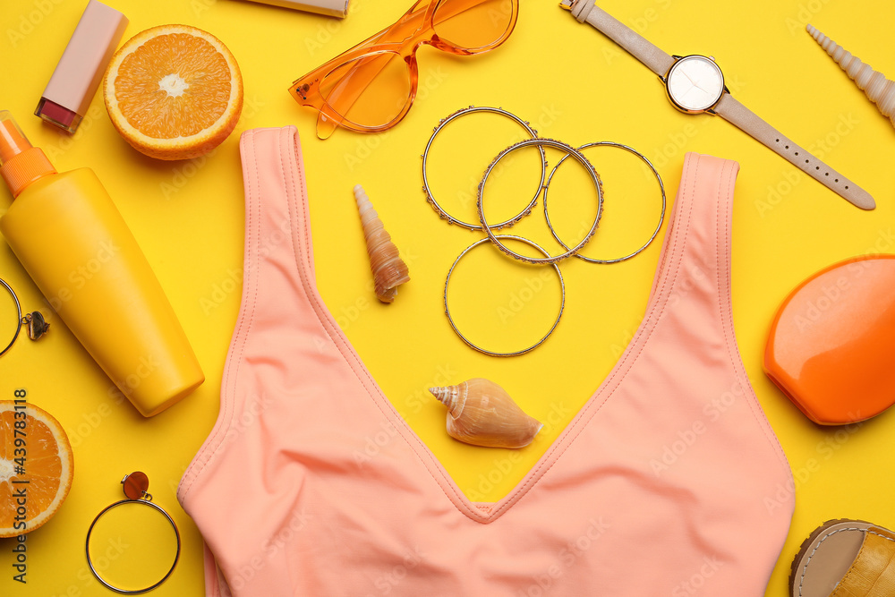 Set of beach accessories and orange on color background, closeup