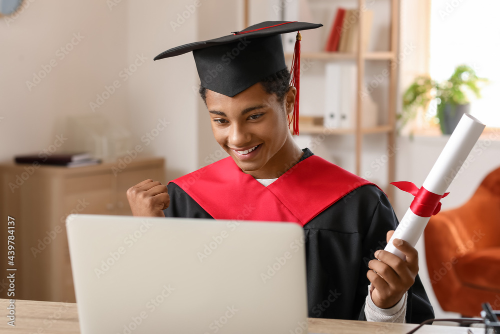 Happy African-American student on his graduation day at home. Concept of online education