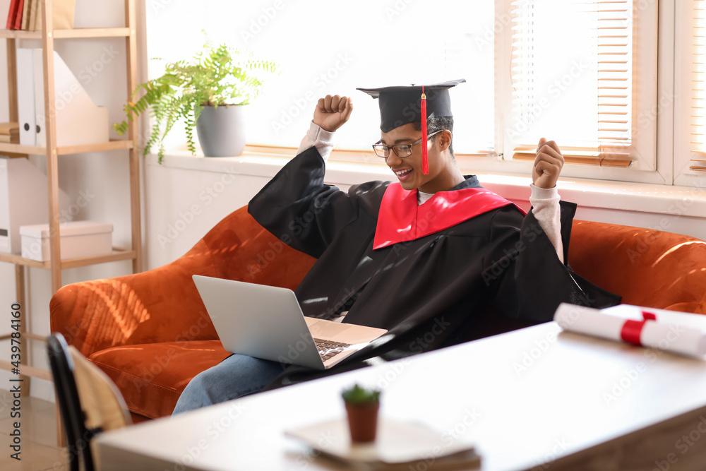 Happy African-American student on his graduation day at home. Concept of online education