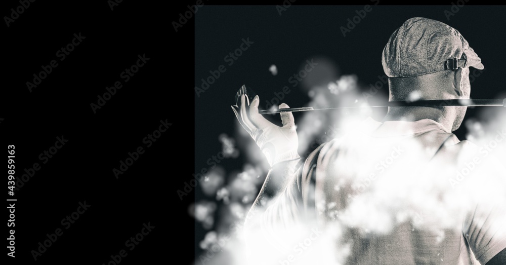 Rear view of senior male golf player holding gold club against smoke effect on black background