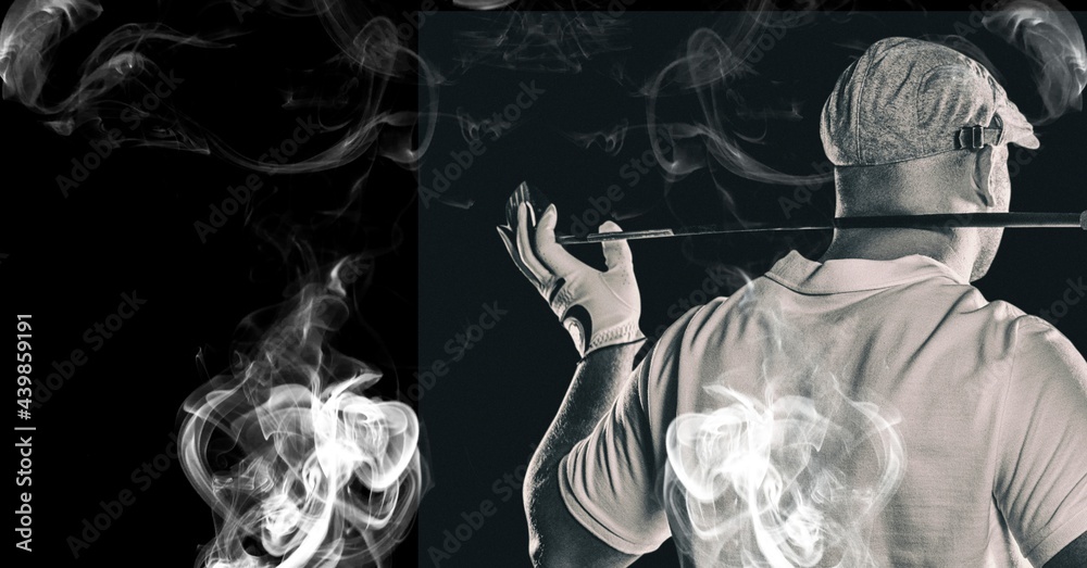 Rear view of senior male golf player holding gold club against smoke effect on black background