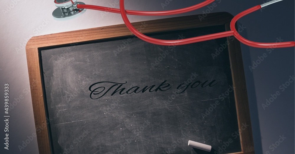 Thank you text, chalk and stethoscope over a wooden slate against grey background