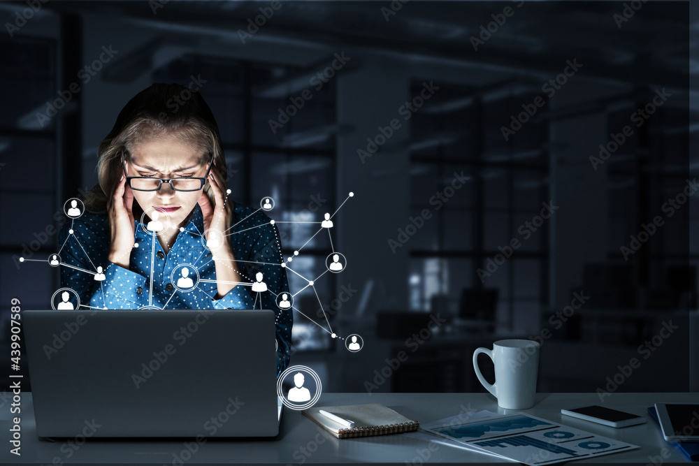 Attractive blonde wearing glasses in dark office using laptop. Mixed media