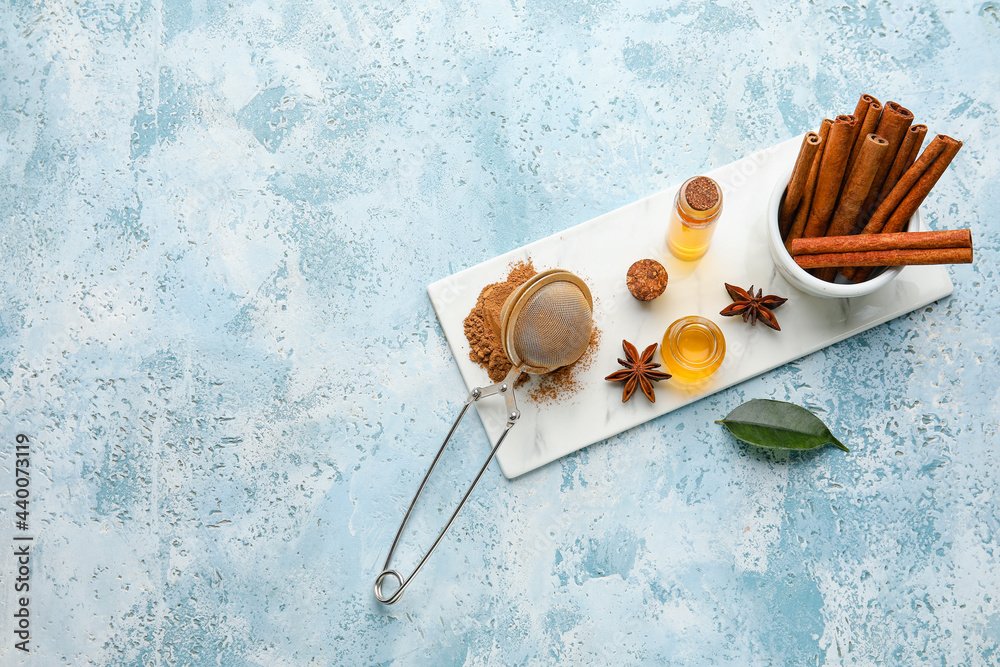 Composition with cinnamon oil, sticks and powder on color background