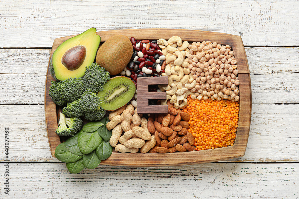 Board with healthy products rich in vitamin E on light wooden background