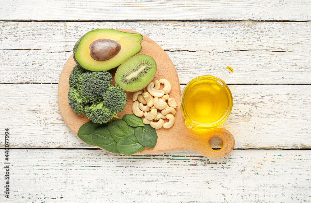 Board with healthy products rich in vitamin E on light wooden background