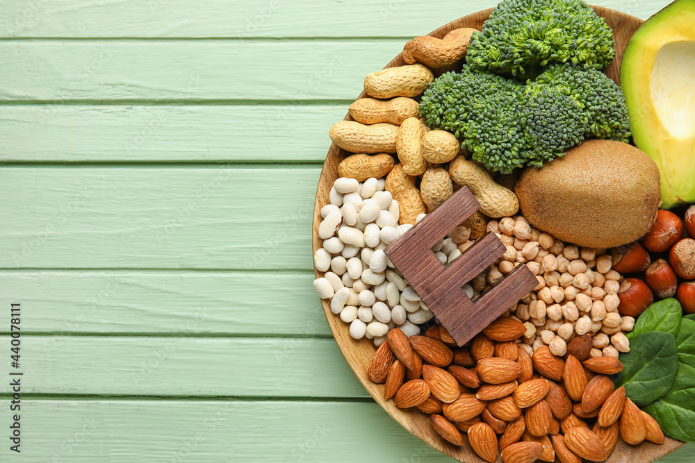 Plate with healthy products rich in vitamin E on color wooden background