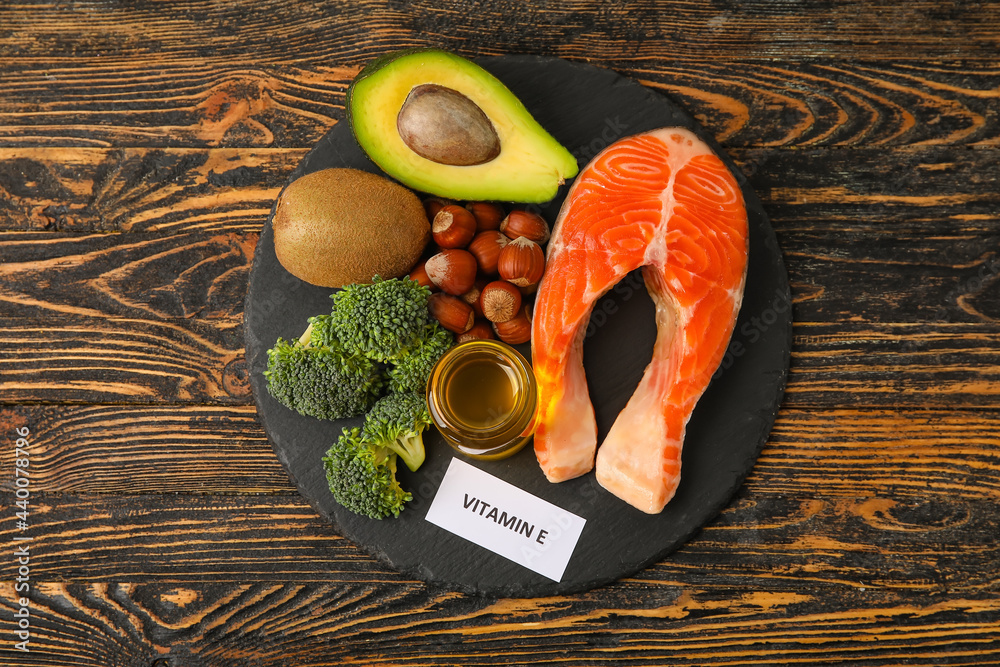 Slate plate with healthy products rich in vitamin E on wooden background