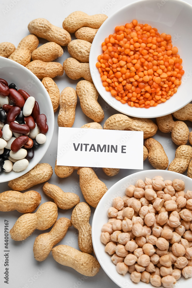 Plates with and different healthy nuts and beans rich in vitamin E on light background, closeup