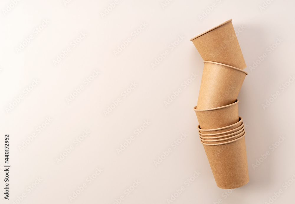 Disposable paper cups on a beige background. A zero-waste concept.