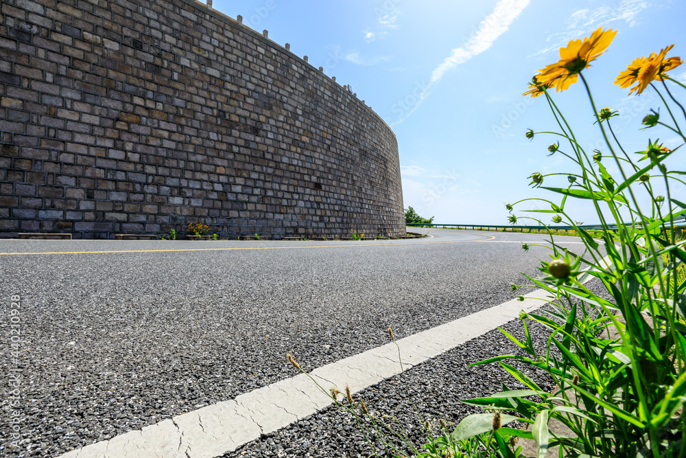 沥青道路和墙壁建筑景观。弯曲的道路背景。