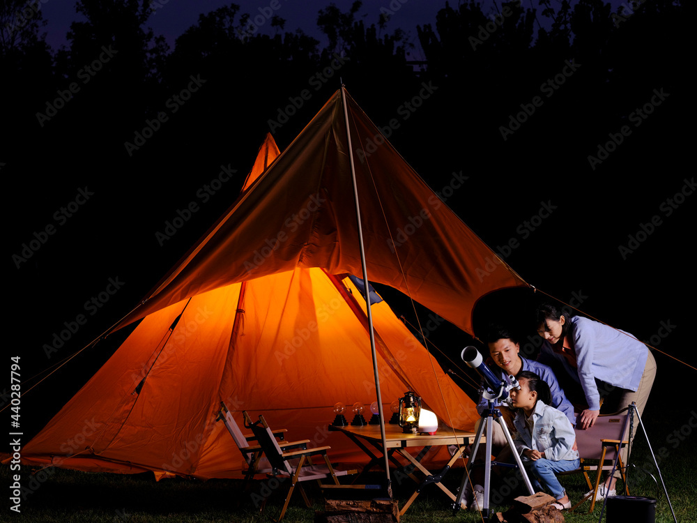 A happy family of three using telescopes outdoors