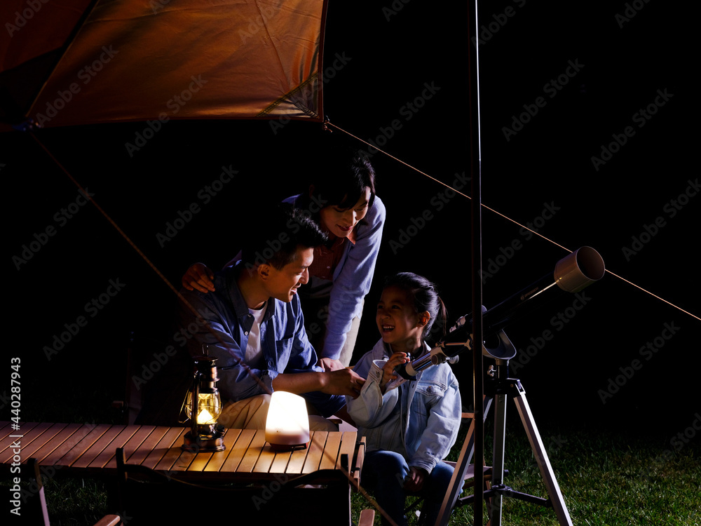 A happy family of three using telescopes outdoors