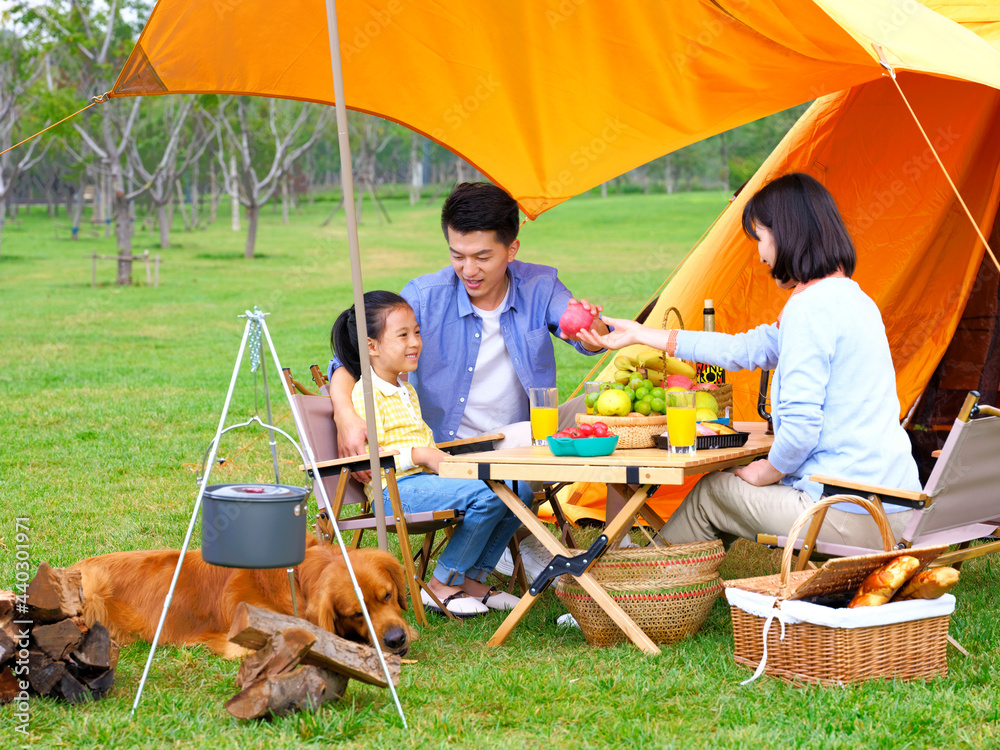 Happy family of three and dog camping out