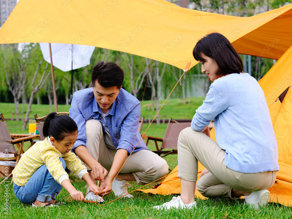 A happy family of three set up tents outdoors