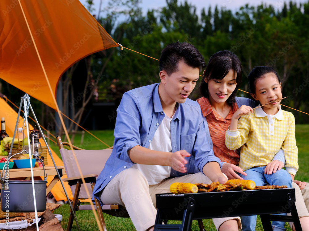 A happy family of three barbecue in the park