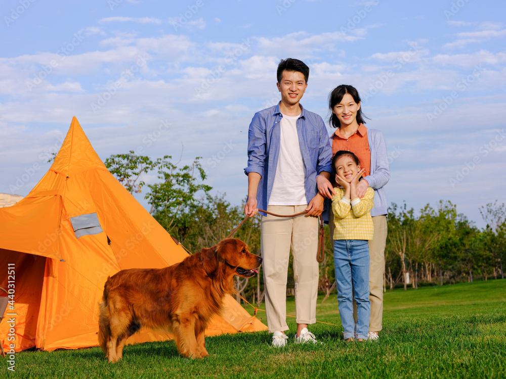 Happy family of three and pet dog in the park