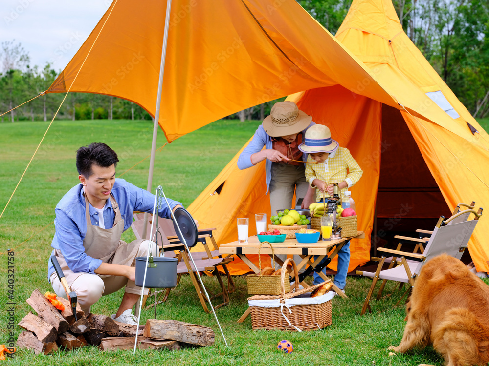 A happy family of three cooks outdoors