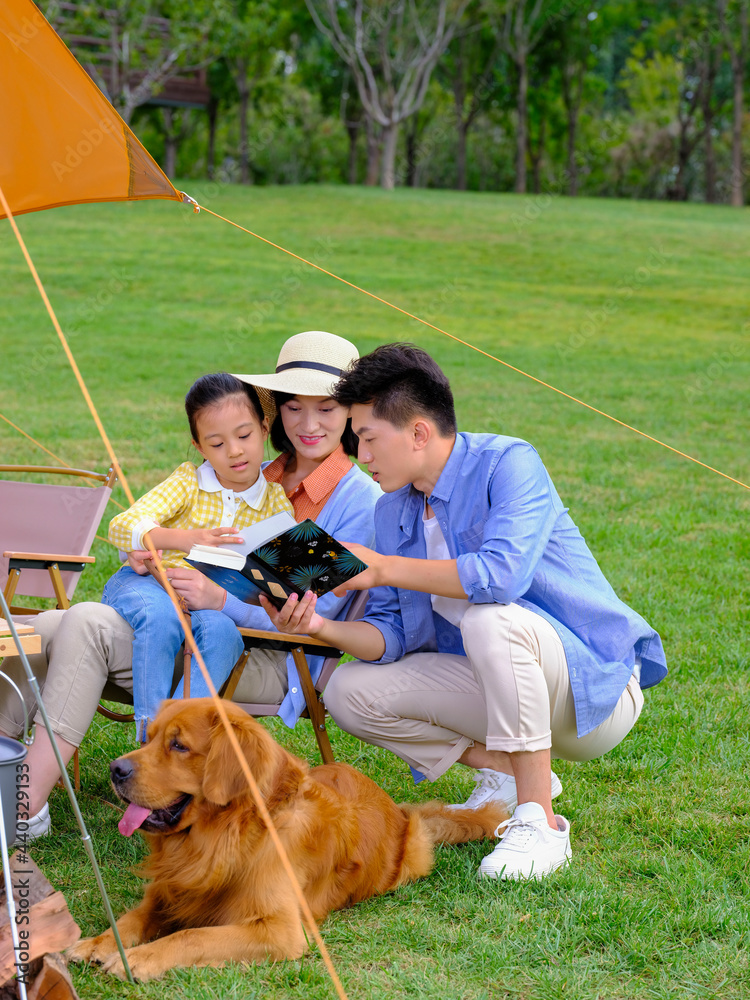 幸福的三口之家和宠物狗在外面读书